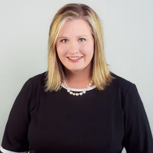 Aundrea Gunter profile picture with neutral background, wearing a black blouse and strings of pearls.
